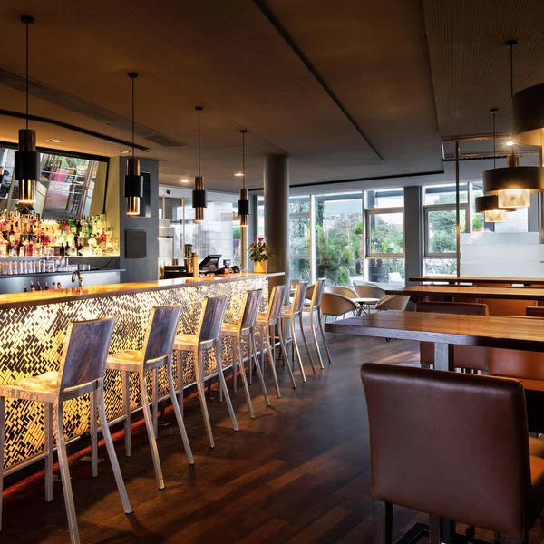 Moderner Bar mit warmem Licht und hohen Metallstühlen