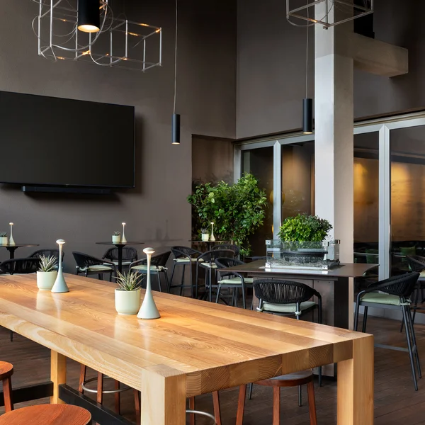 Interno di un moderno ristorante con tavoli, sedie e TV a parete
