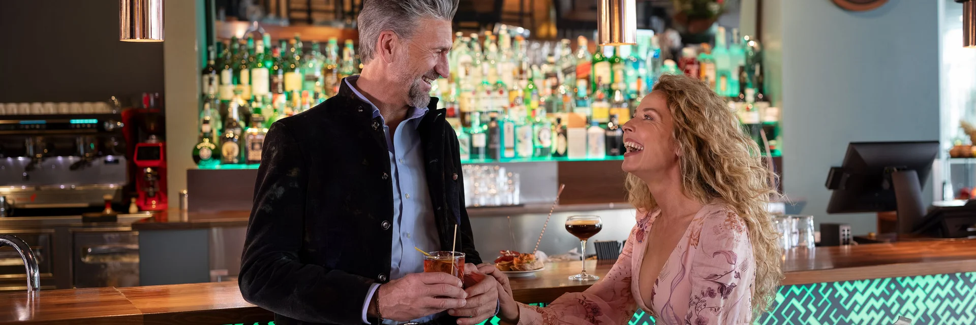 Coppia felice che conversa e beve al bar moderno con luci soffuse