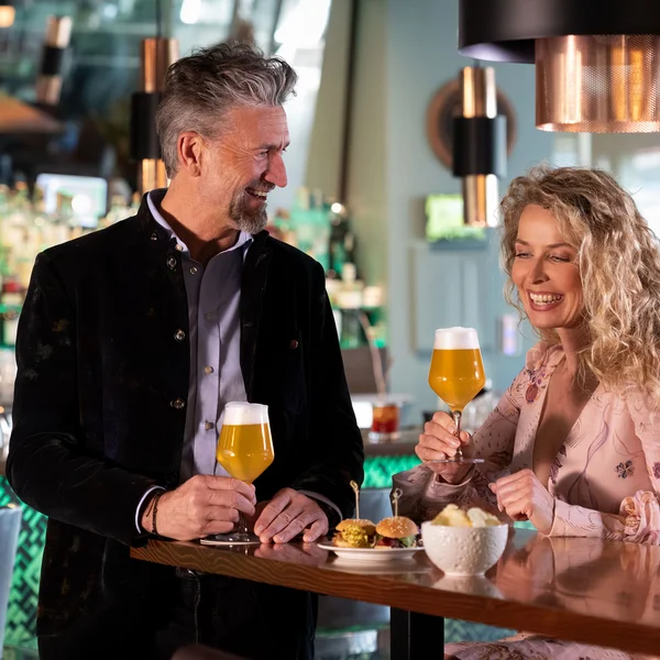 Smiling couple with beer and food at a modern bar