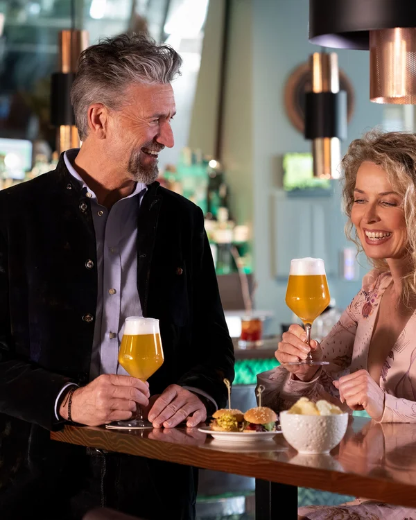 Coppia sorridente con birra e cibo in un bar moderno