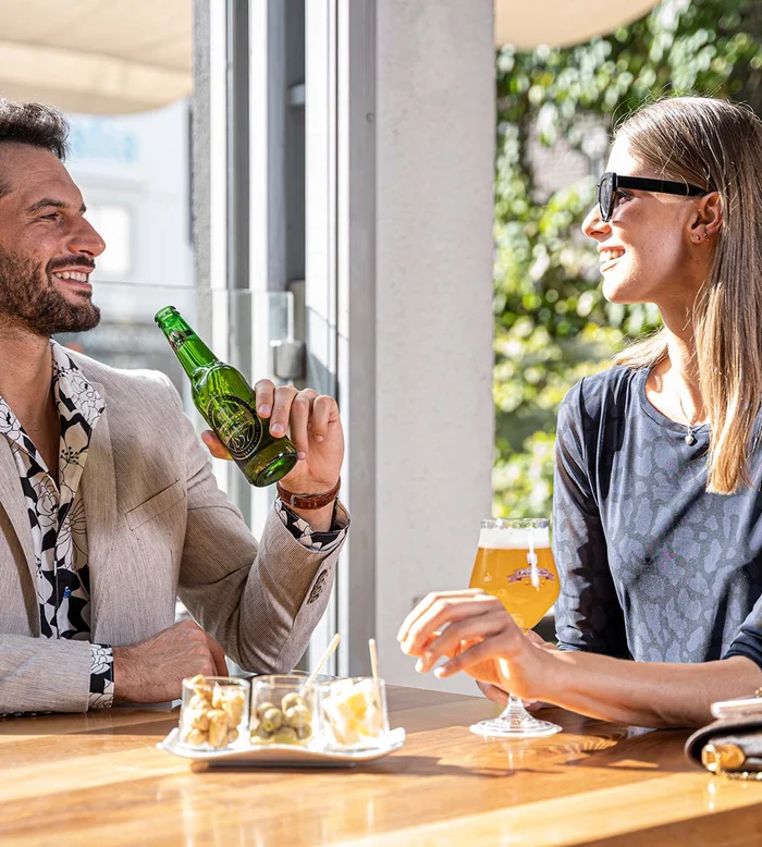 Uomo e donna sorridenti che bevono birra al tavolo all'aperto