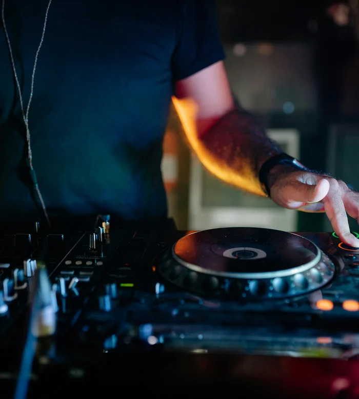 Primo piano di un DJ che mixa tracce con consolle in un club