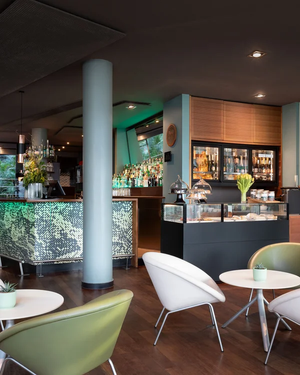 Interno moderno di un bar con sedie bianche e verdi e bancone luminoso