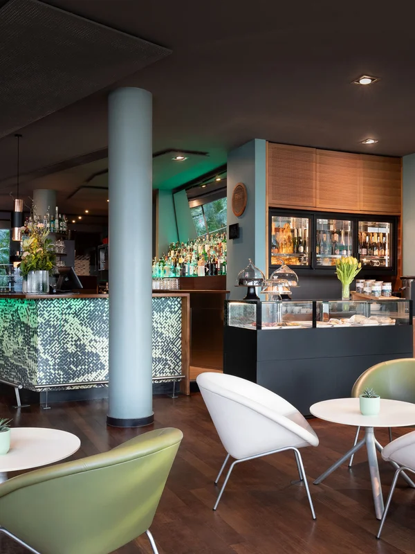 Interno moderno di un bar con sedie bianche e verdi e bancone luminoso