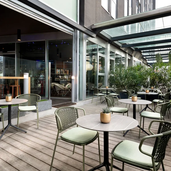 Terrazza coperta con tavoli rotondi e sedie verdi