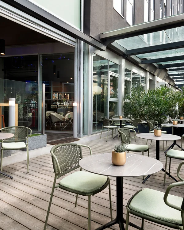 Covered terrace with round tables and green chairs